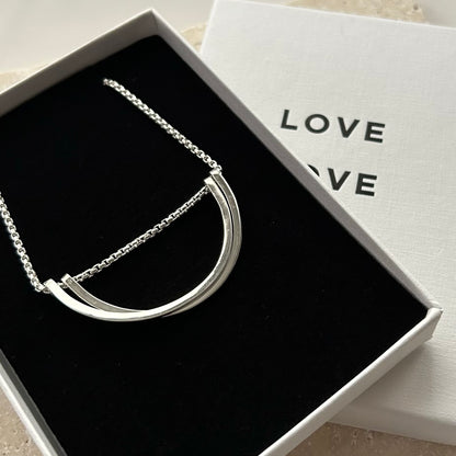 Silver necklace in a box with 'LOVE' text on a light background