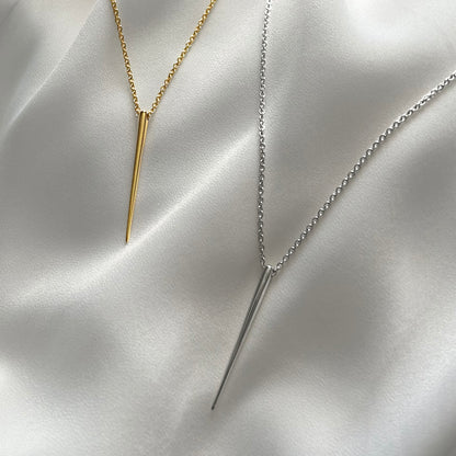 Two necklaces with spike pendants on a satin surface