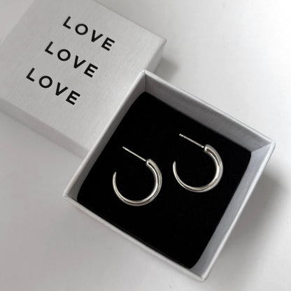 Silver hoop earrings in a box with 'LOVE' text on a light gray background