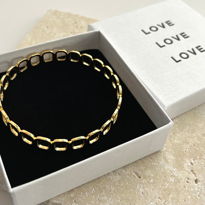 Gold bracelet in a white box with 'LOVE' text on a light surface
