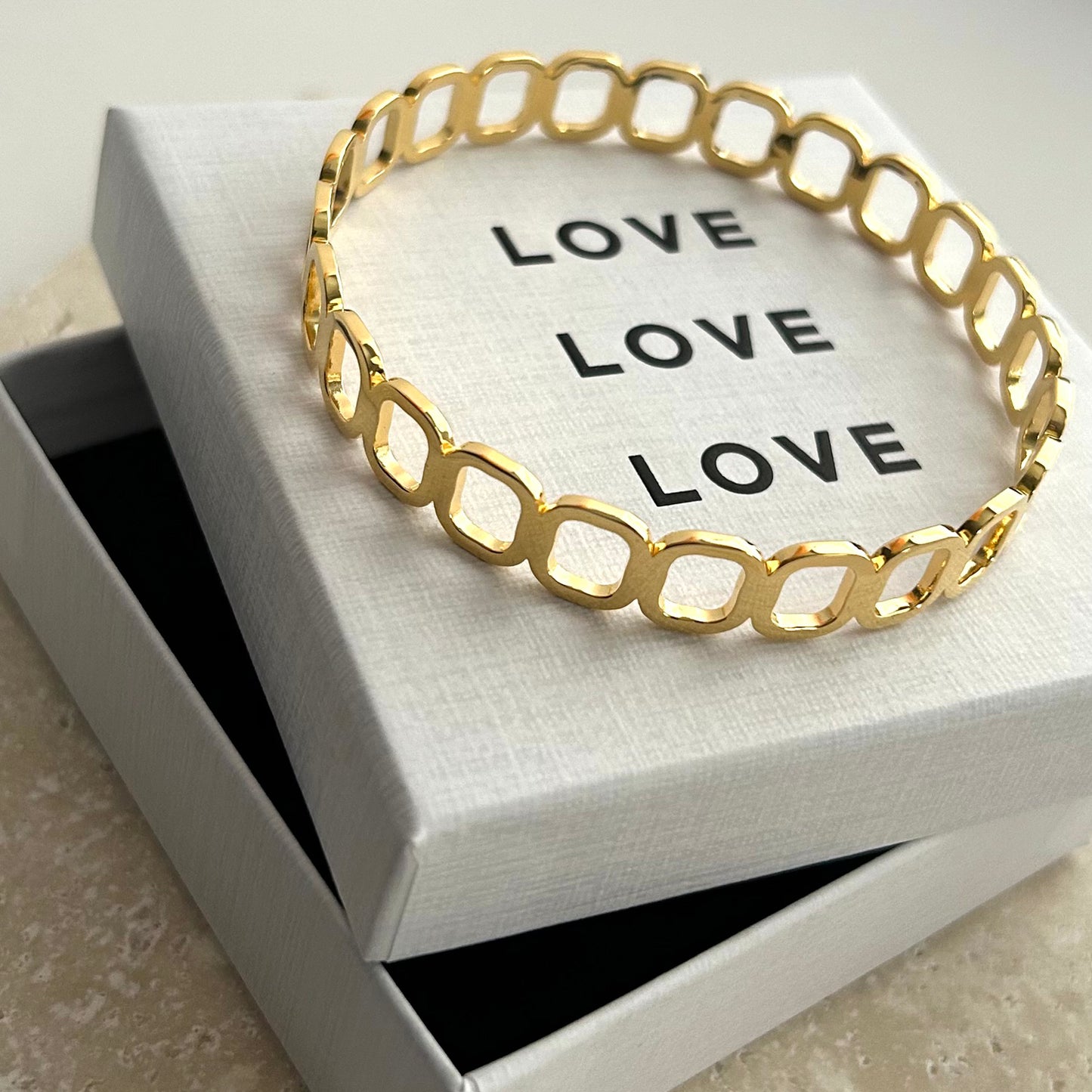Gold bracelet on a white box with 'LOVE' text