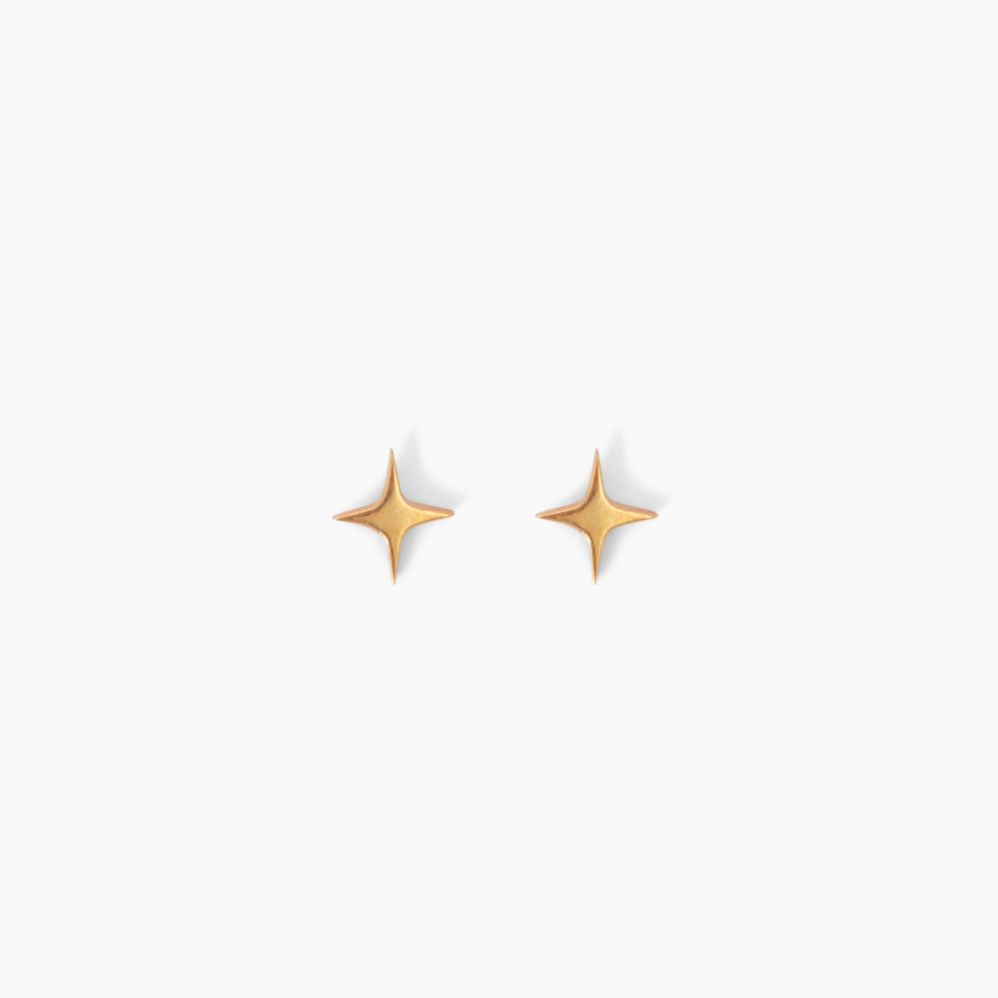 Pair of star shaped gold stud earrings on a white background