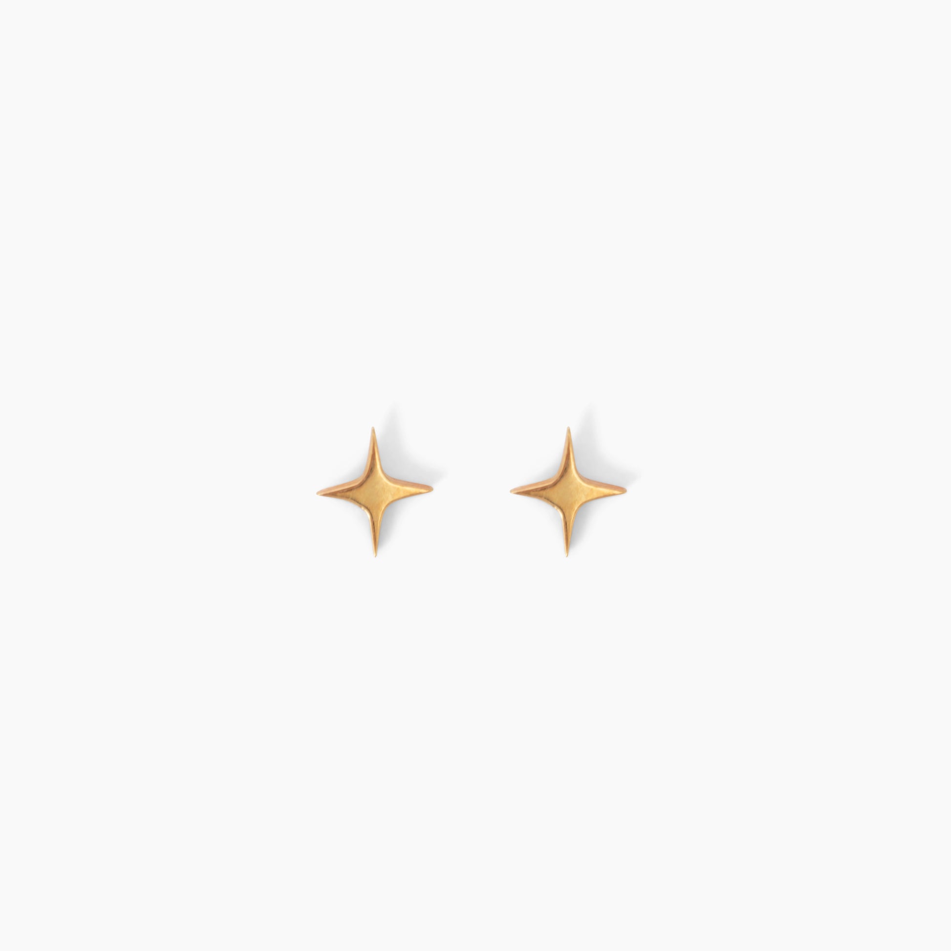 Pair of star shaped gold stud earrings on a white background
