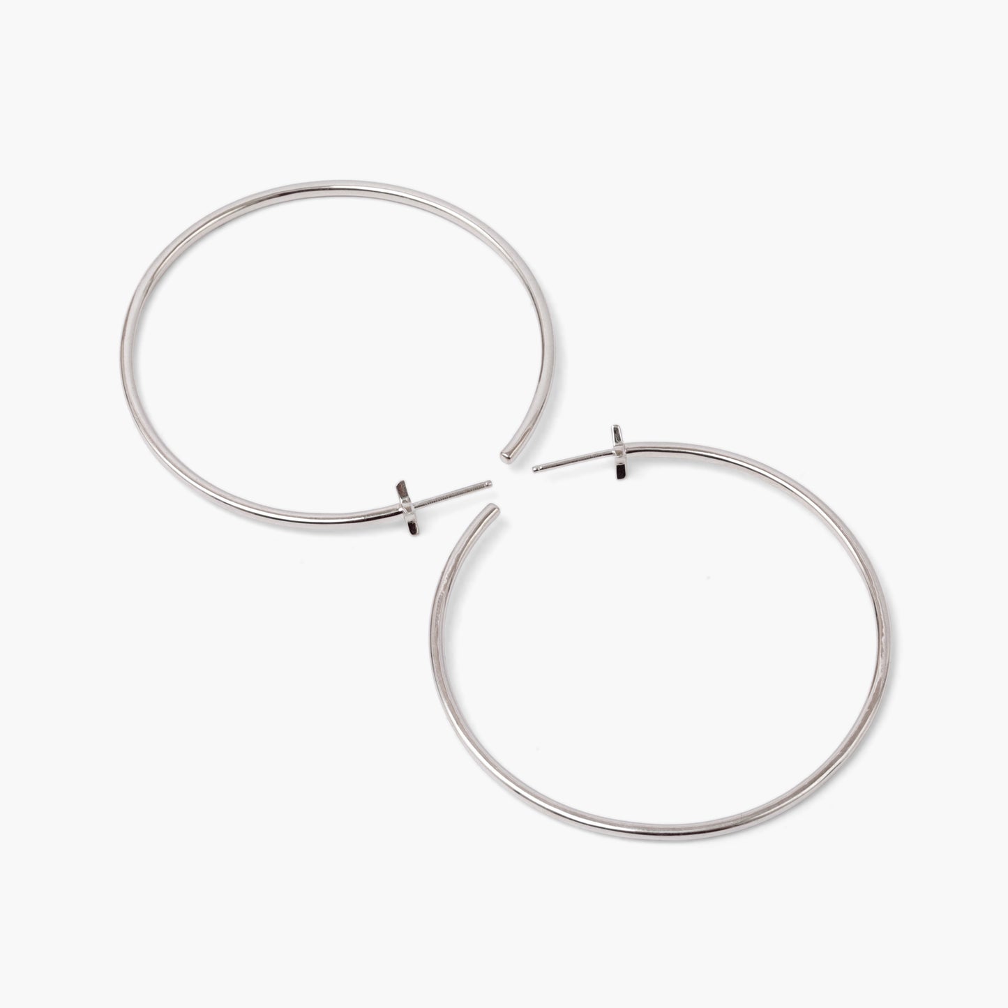 A pair of silver-colored hoop earrings with starburst designs attached to the hoops, positioned against a white background.