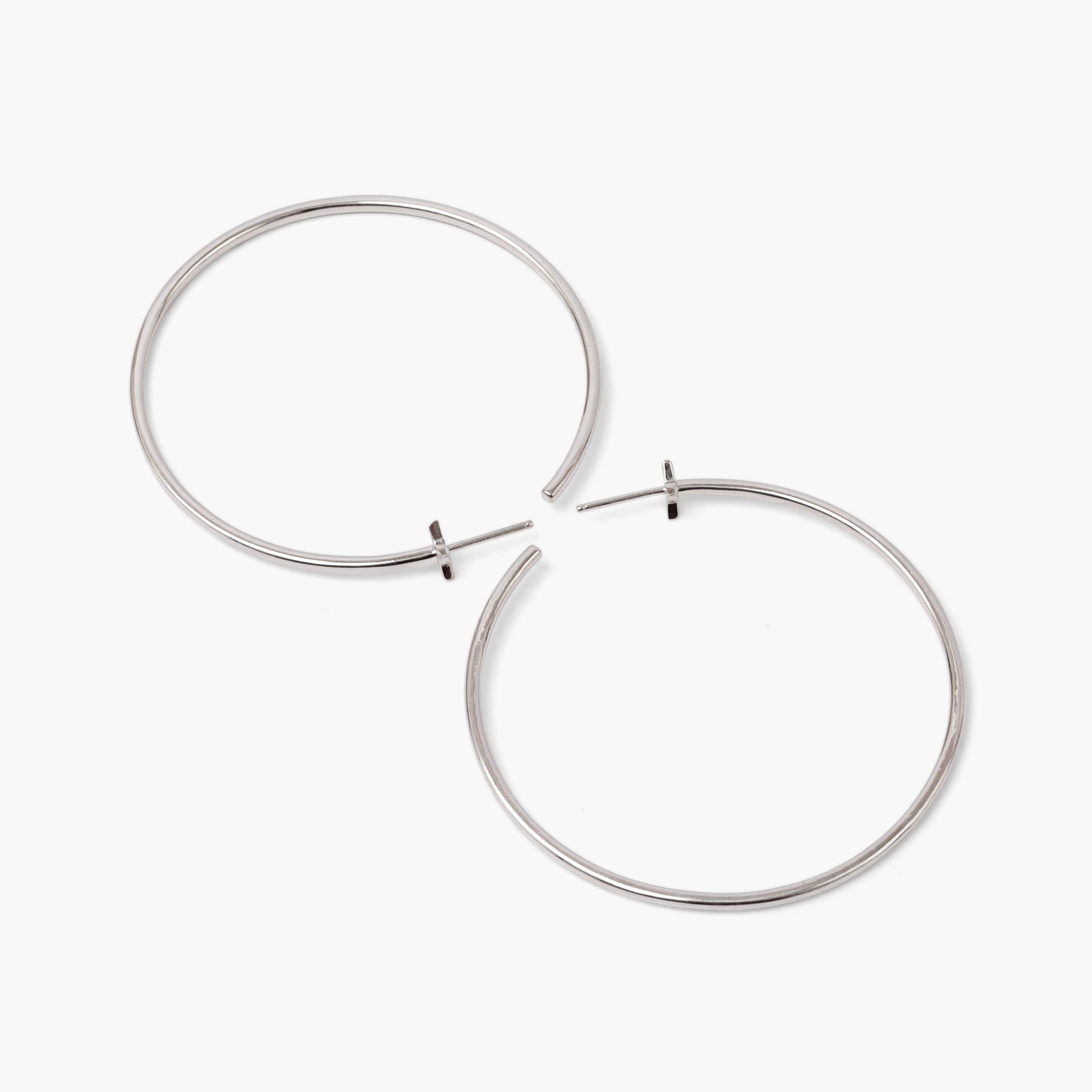 A pair of silver-colored hoop earrings with starburst designs attached to the hoops, positioned against a white background.
