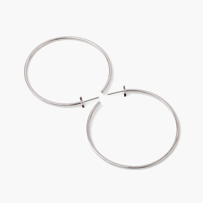 A pair of silver-colored hoop earrings with starburst designs attached to the hoops, positioned against a white background.