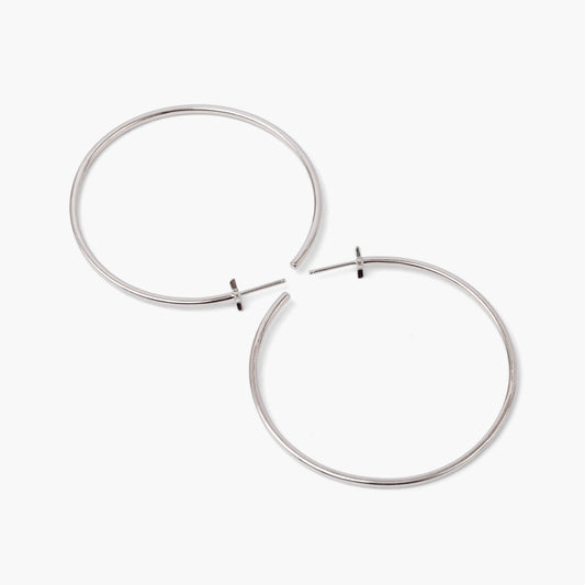A pair of silver-colored hoop earrings with starburst designs attached to the hoops, positioned against a white background.
