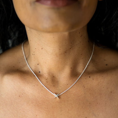 Close-up of a person wearing a silver necklace with a star pendant.