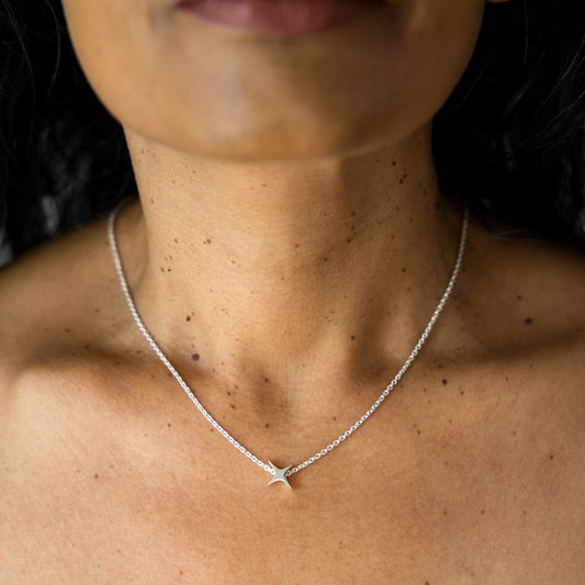 Close-up of a person wearing a silver necklace with a star pendant.