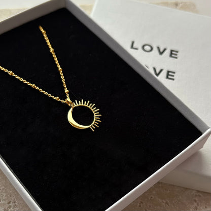 Gold necklace with a unique pendant in a box labeled 'LOVE'.
