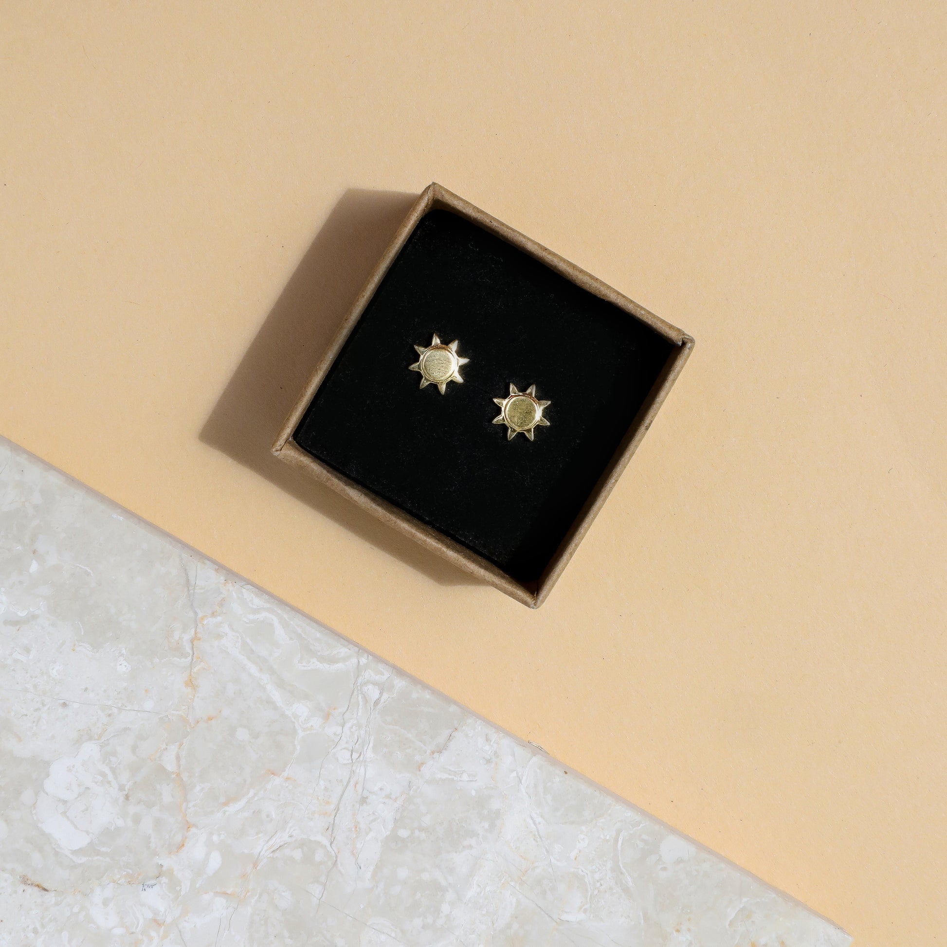 Gold sunshine stud earrings in a box