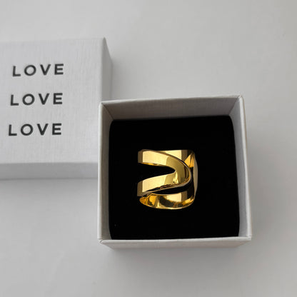 Gold ring in a box with 'LOVE' text on a light gray background