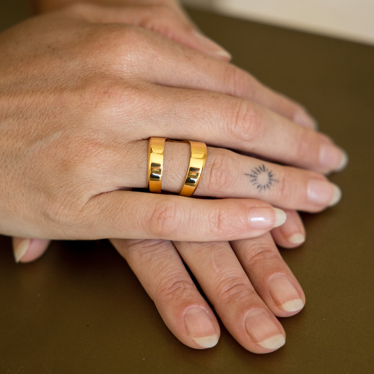 Close-up of hands with gold ring on a brown surface