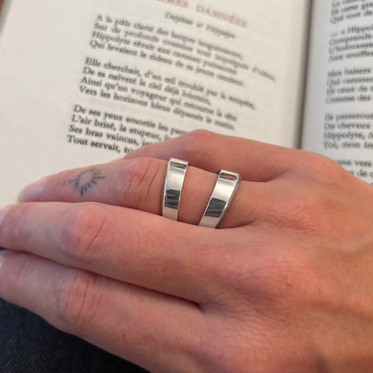 Close-up of a hand wearing a silver ring with an open book in the background.