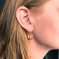 Gold teardrop earring worn by a person with blonde hair.