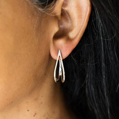 Close-up of an ear wearing a silver earring with dark hair in the background