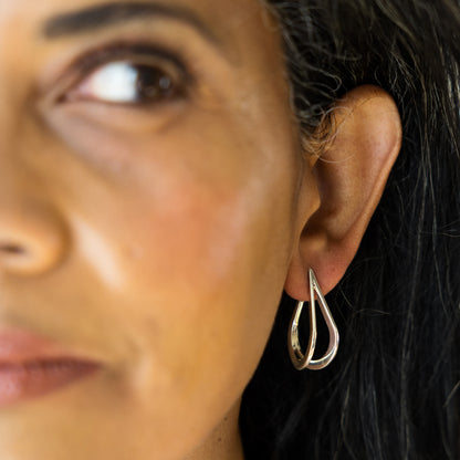 Close-up of a woman wearing a silver teardrop earring.
