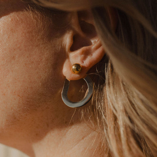 Close up of a person wearing circular geometric earrings