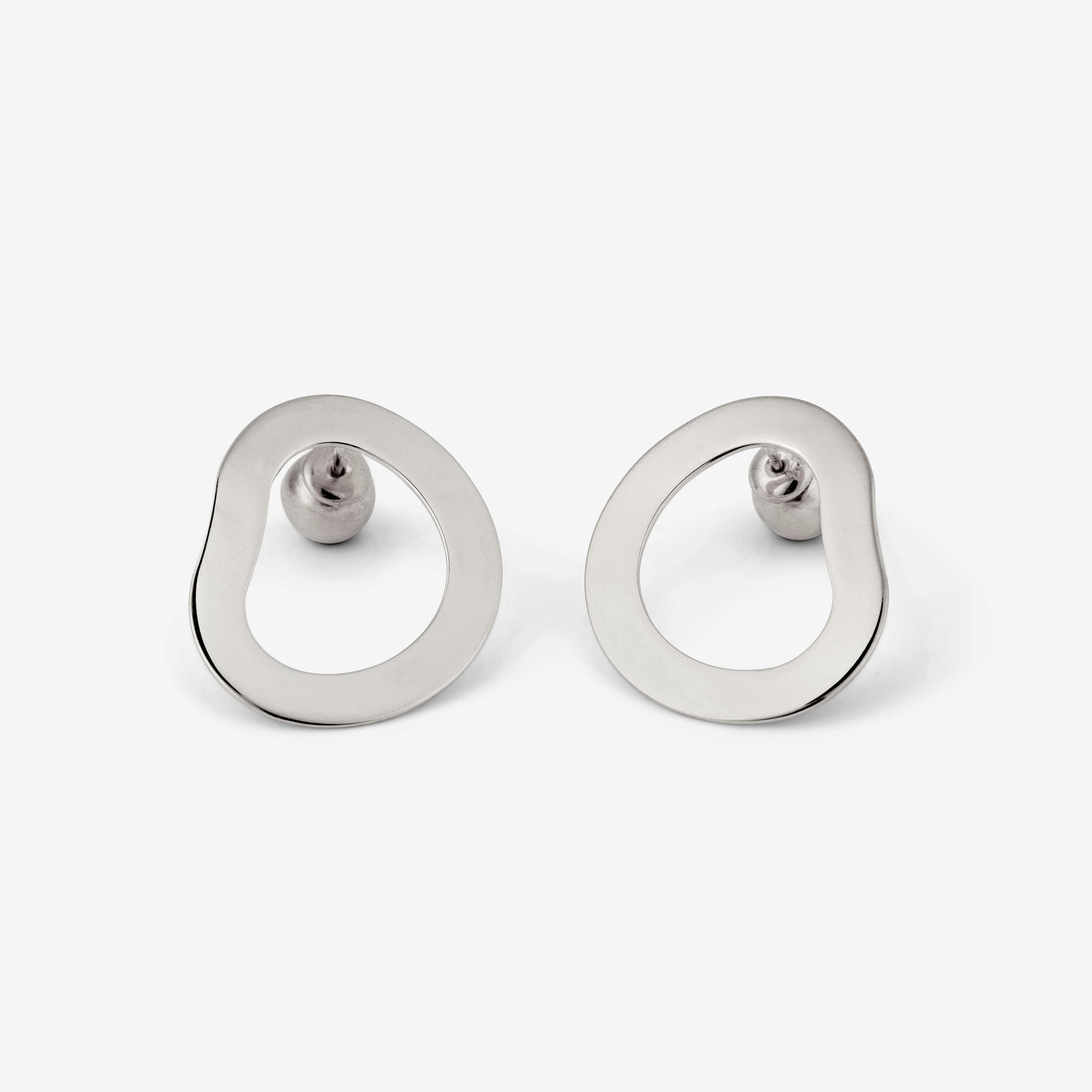 A pair of silver-colored geometric earrings with an open-oval shape accompanied by two small orb-style backings on a white background.