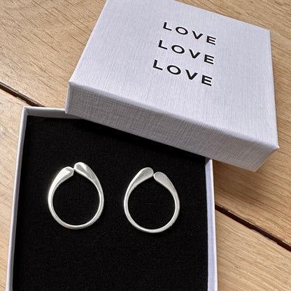 Silver hoop earrings in a box with 'LOVE' text on a wooden surface