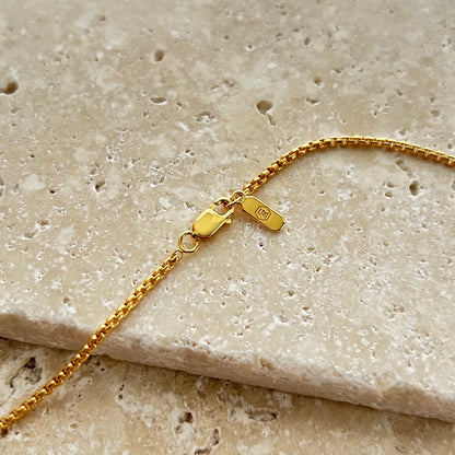 Gold rolo chain on a textured beige surface