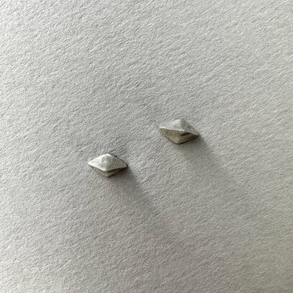 Pair of silver pointed stud earrings on a grey background