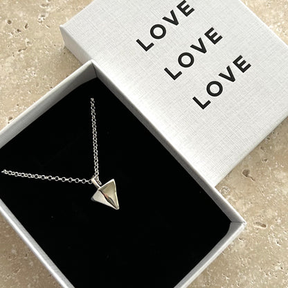 Silver necklace with a pyramid pendant in a box labeled 'LOVE'.