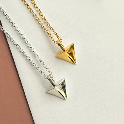 Two pyramid-shaped pendants on gold and silver chains against a neutral background