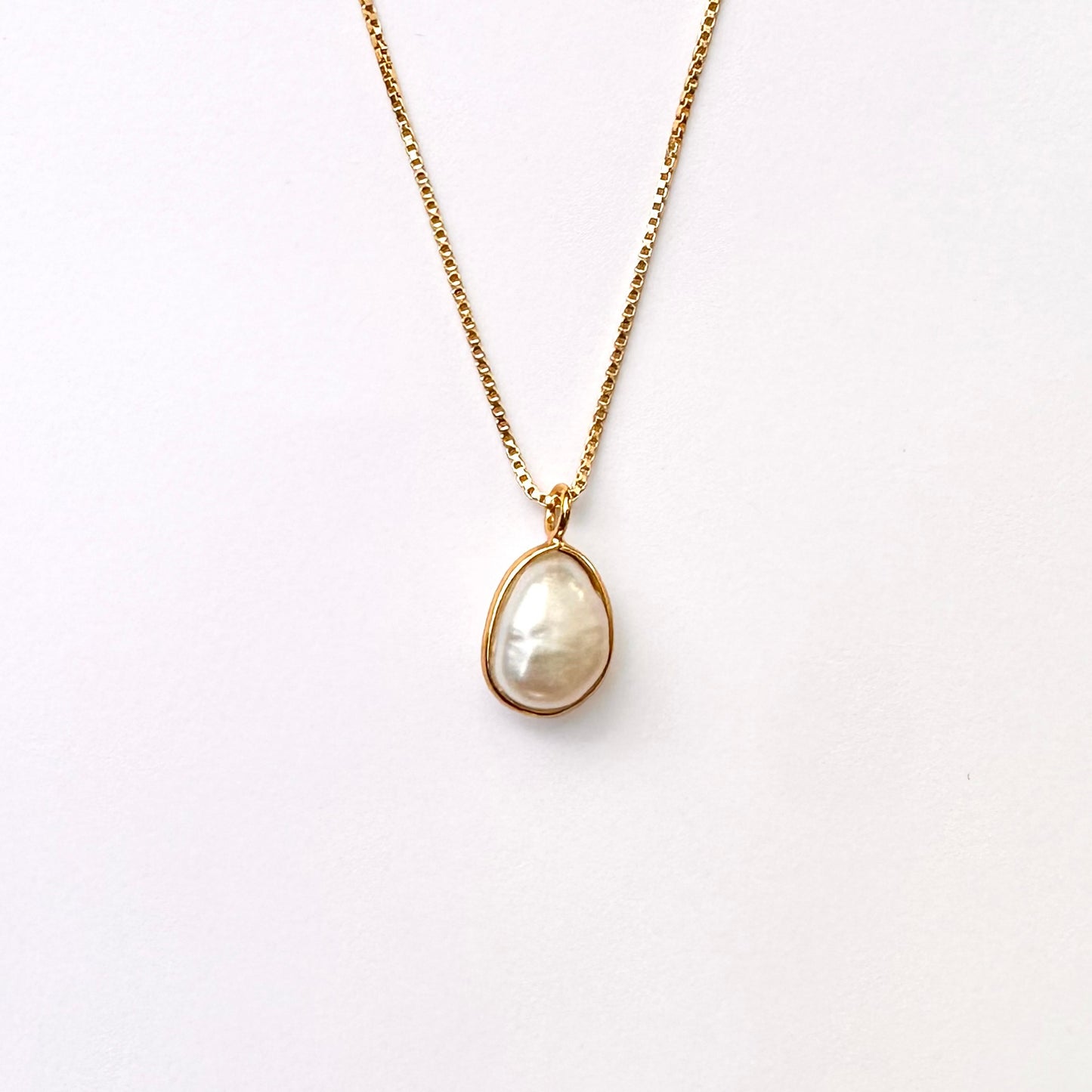 A baroque pearl necklace with a gold vermeil setting on a box-style chain.