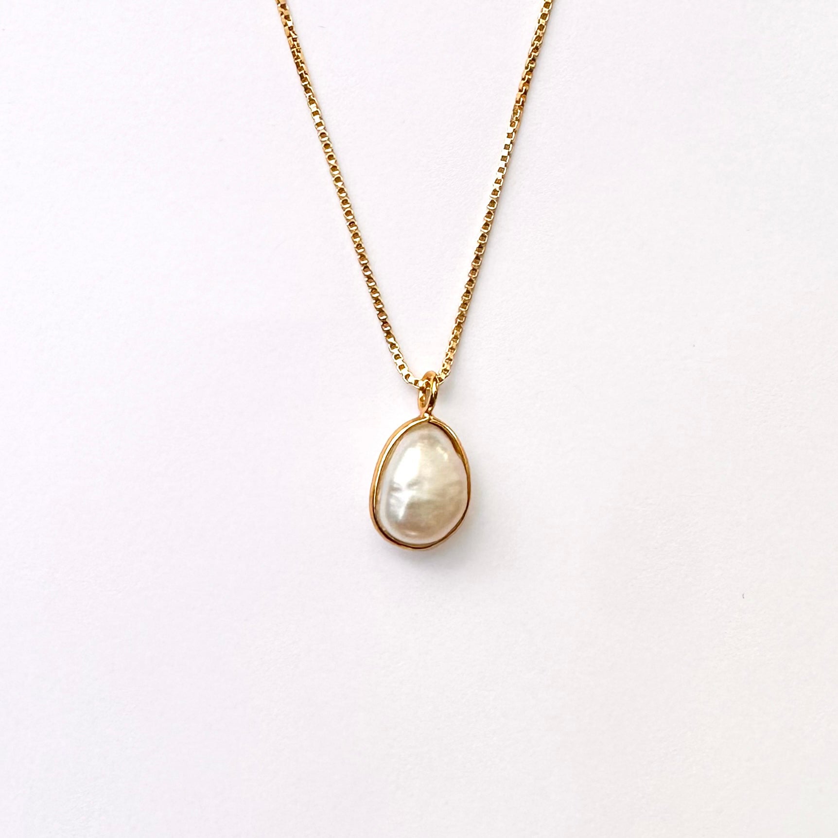 A baroque pearl necklace with a gold vermeil setting on a box-style chain.