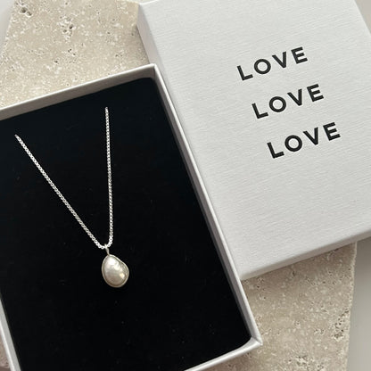 Pearl necklace in a jewelry box with 'LOVE' text