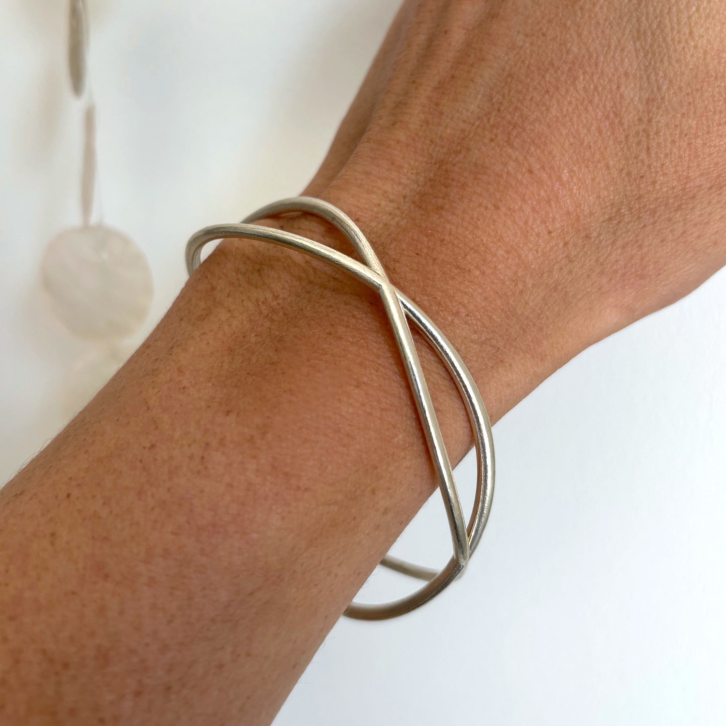Silver wave bracelet on a wrist with a plain background