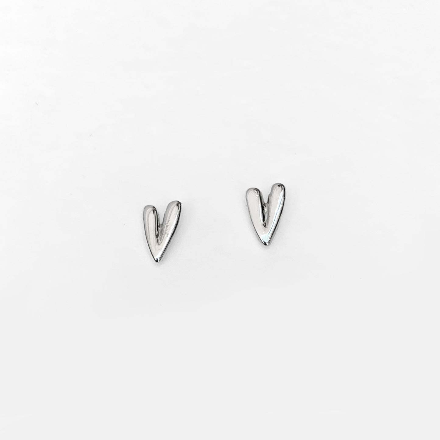A pair of silver-colored stud earrings in the shape of elongated hearts.