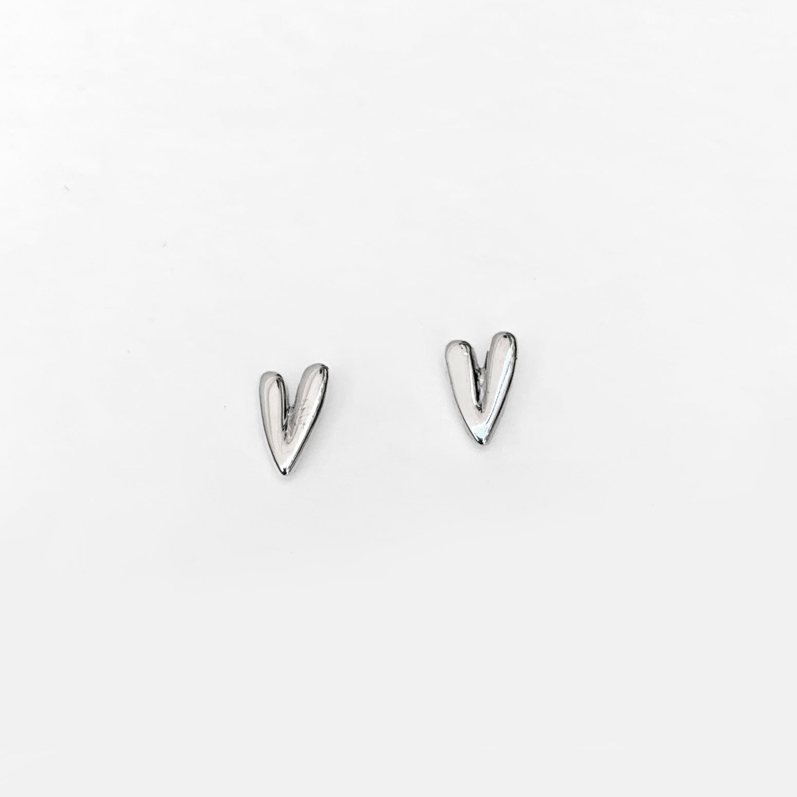 A pair of silver-colored stud earrings in the shape of elongated hearts.