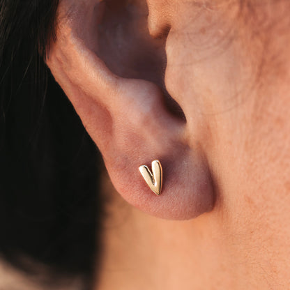 Close up of a person wearing a heart-shaped stud earring