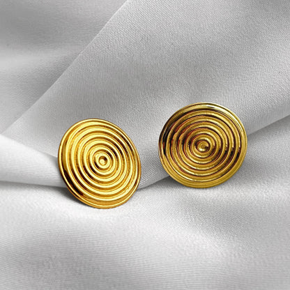 Pair of gold spiral earrings on a light gray fabric background