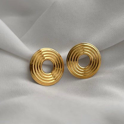 Gold spiral earrings on a white fabric background