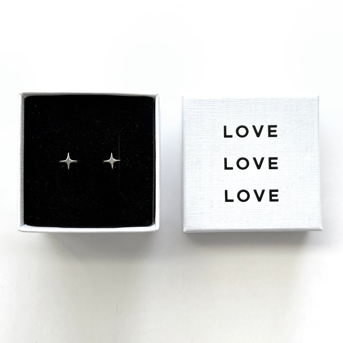 Star-shaped earrings in a box with 'LOVE' text on a white background