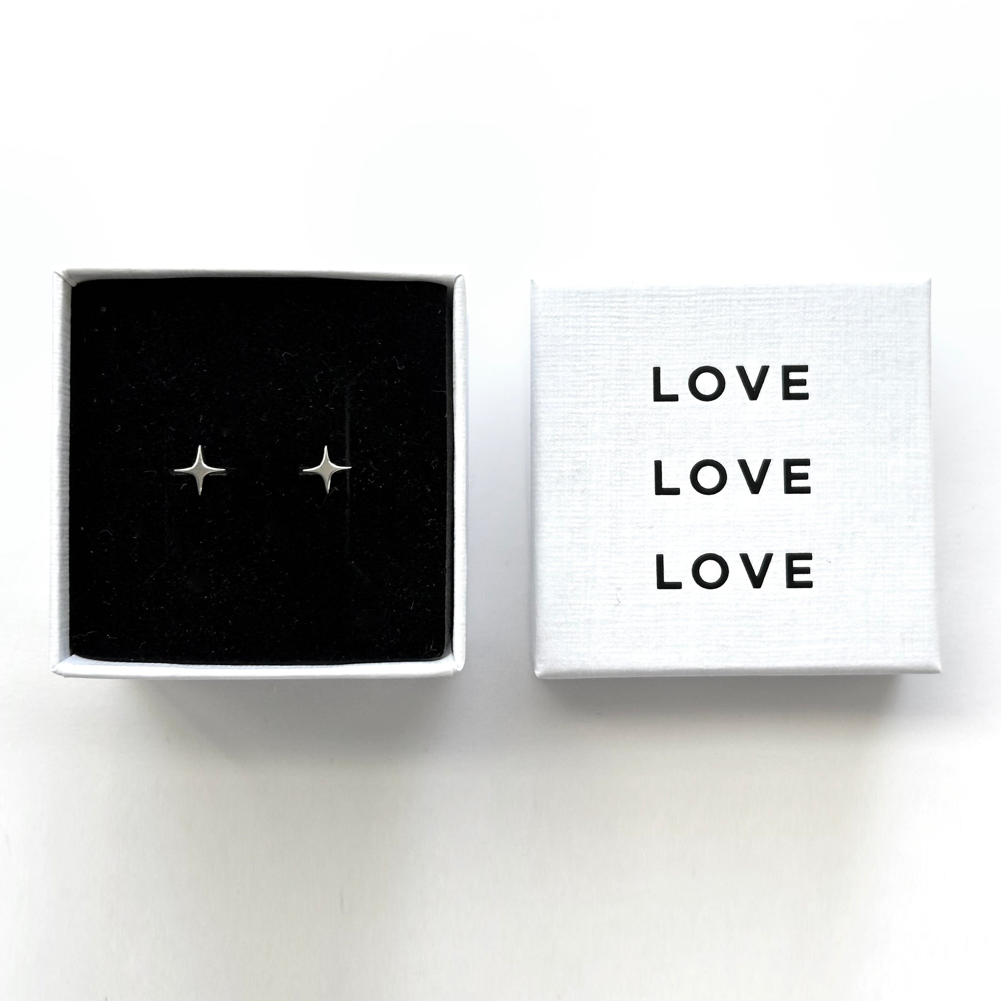 Star-shaped earrings in a box with 'LOVE' text on a white background