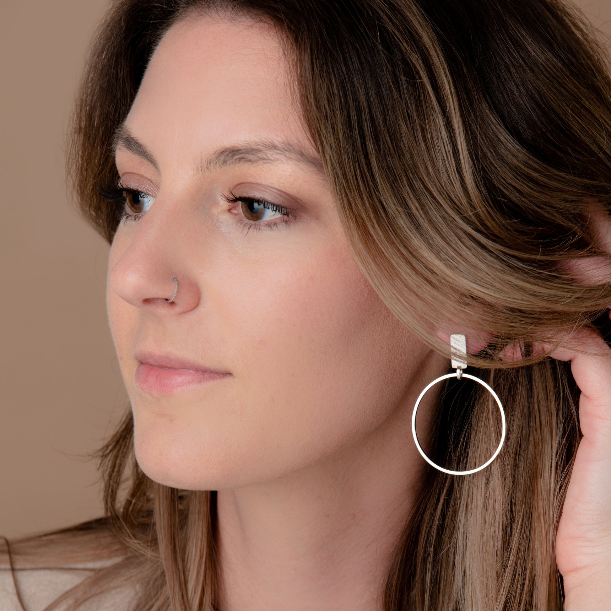Person wearing silver hoop earrings.