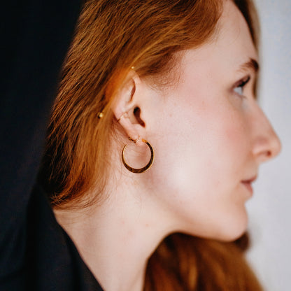 Person wearing a gold hoop earring.