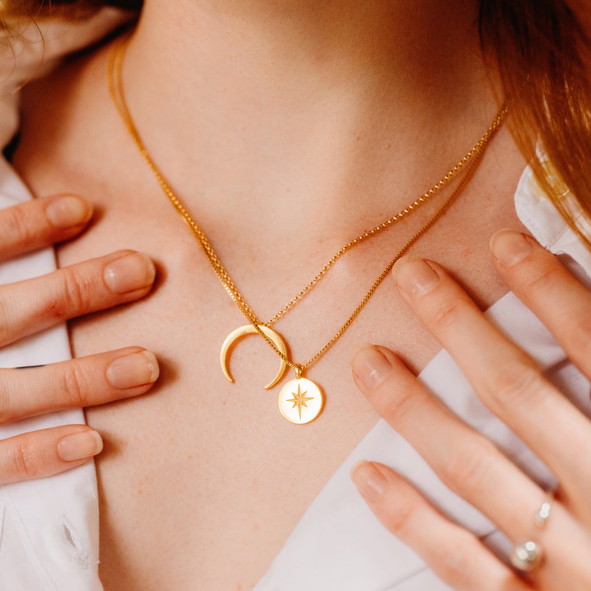 Person wearing a a necklace with a curved pendant and a circle necklace.