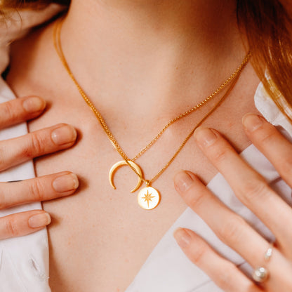 Person wearing a a necklace with a curved pendant and a circle necklace.