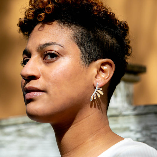 Person wearing a silver leaf-shaped earring.