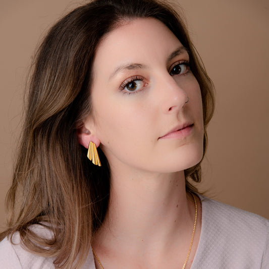 Person wearing a shell-shaped gold earring.